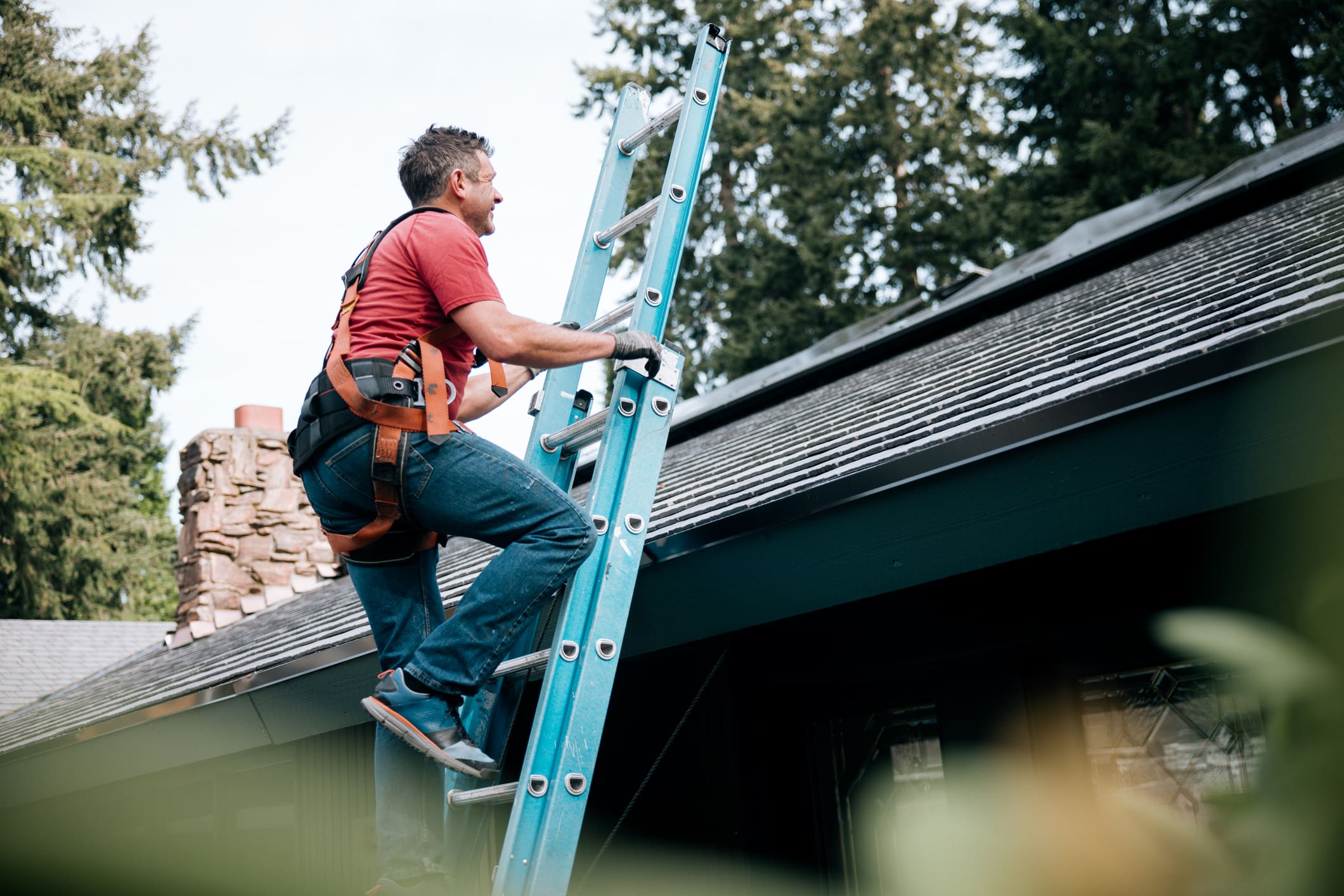 Man climbing a ladder to inspect or repair a roof.